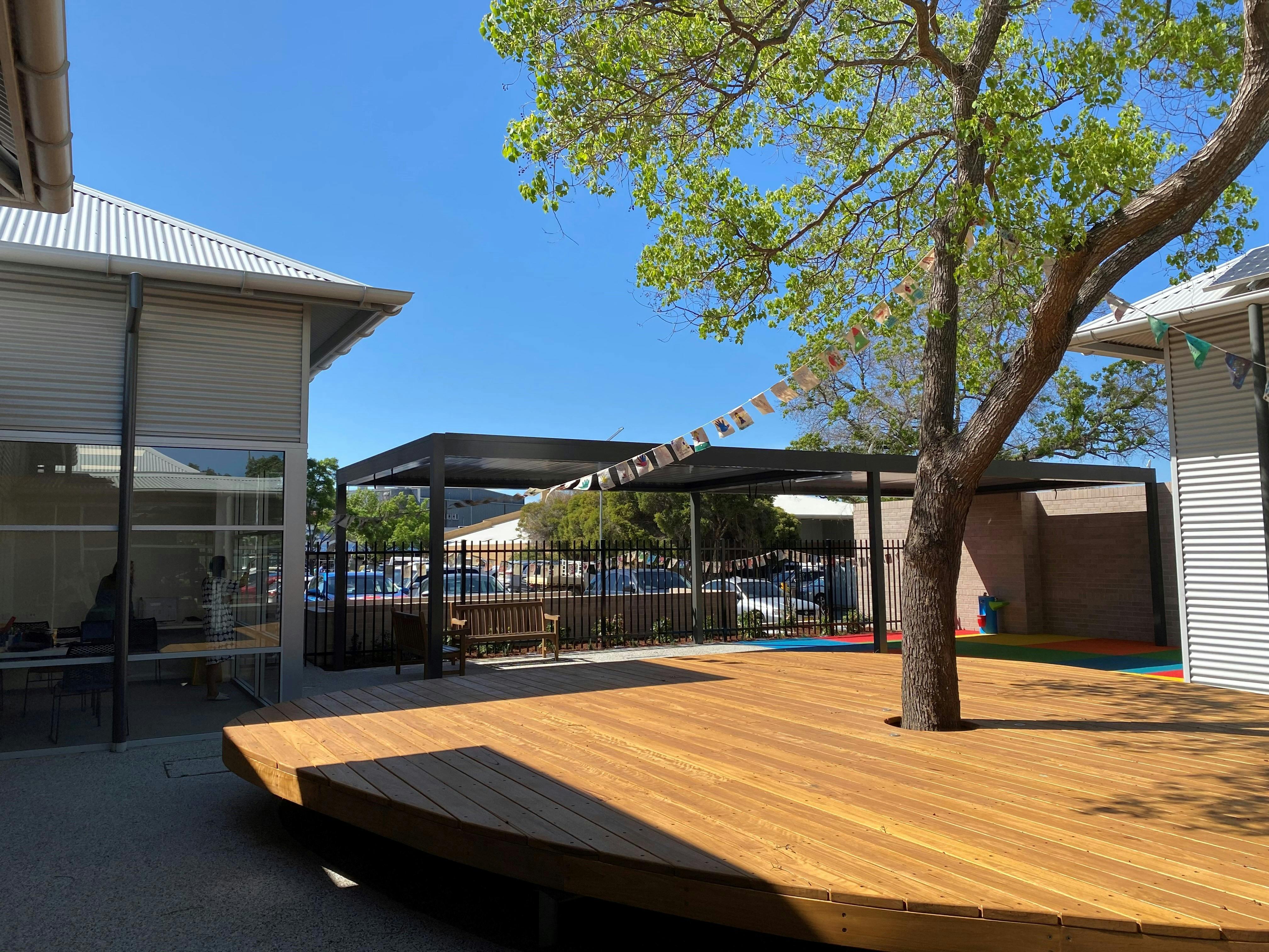 Deck surrounding large tree in courtyard.