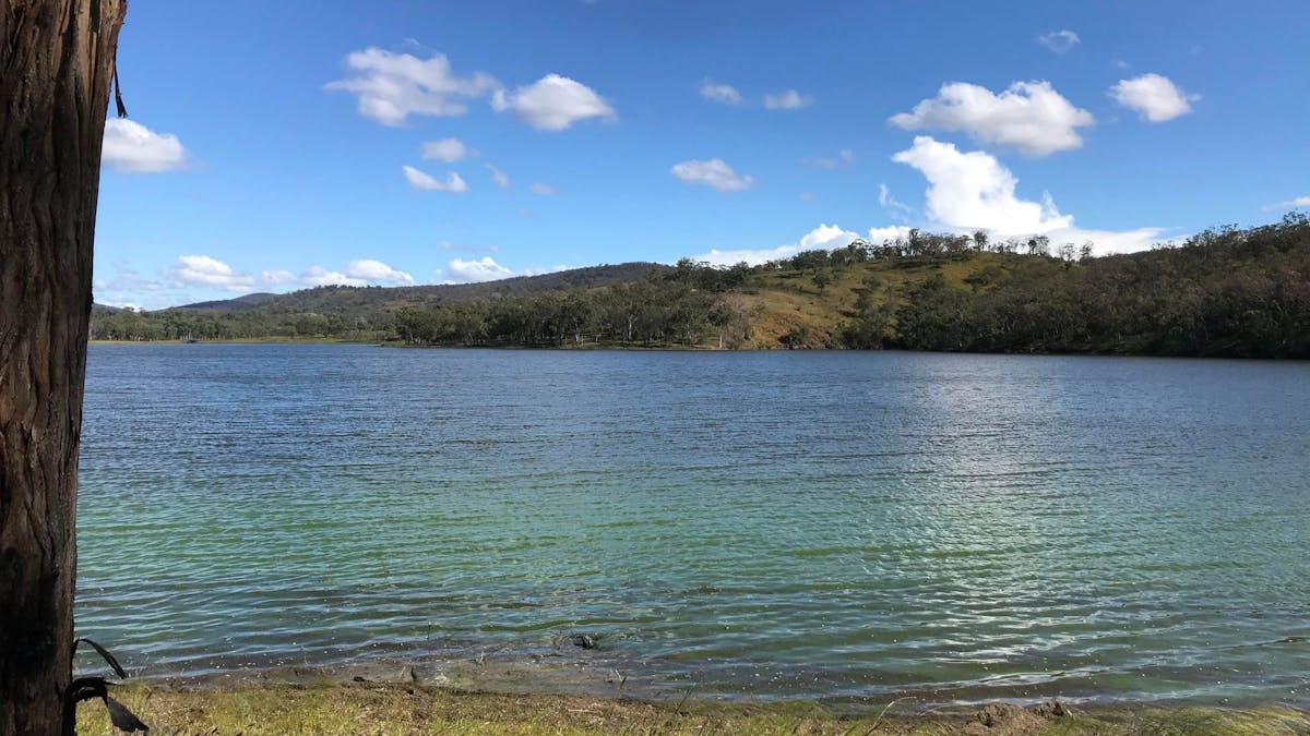 An image of Connolly Dam's green water with hills in the background