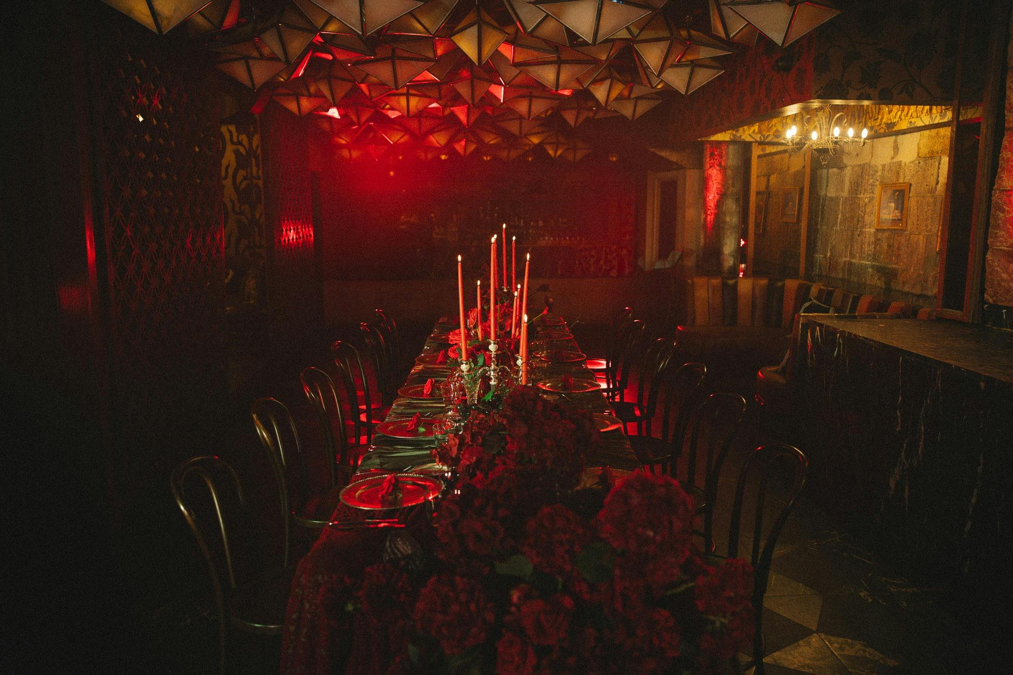 An image of a banquet table with candles and red flowers