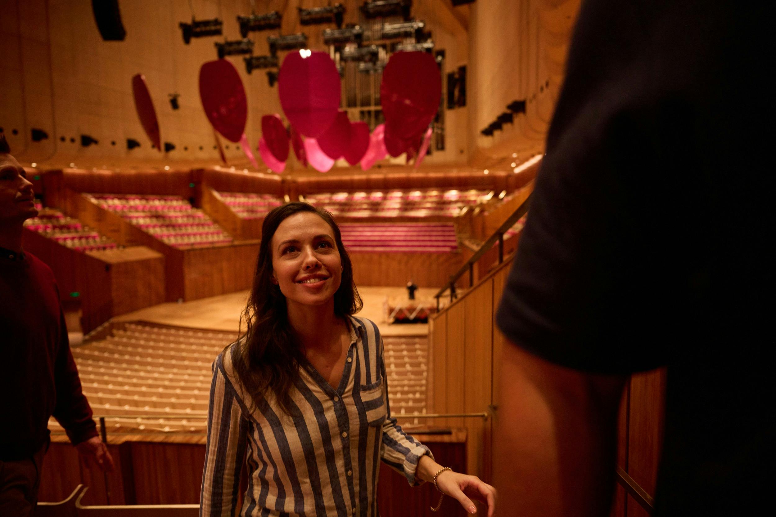 Woman with long brown hair in a blue and white stripe shirt walking through the Concert Hall