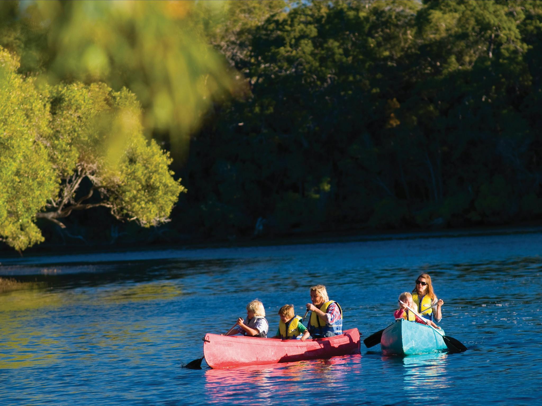 Two canoes with people in them on a river