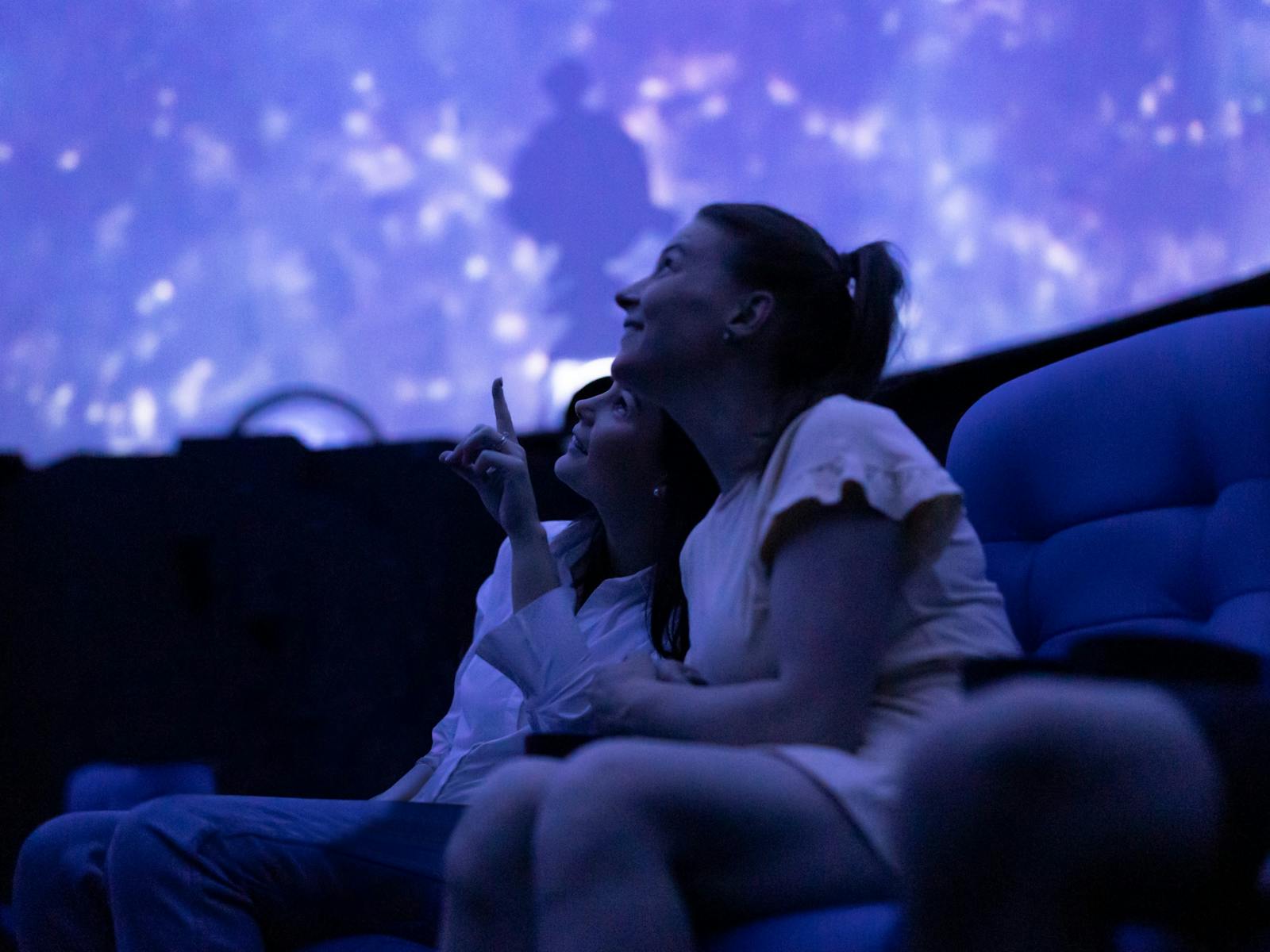 Two people look up at a full-dome screen.