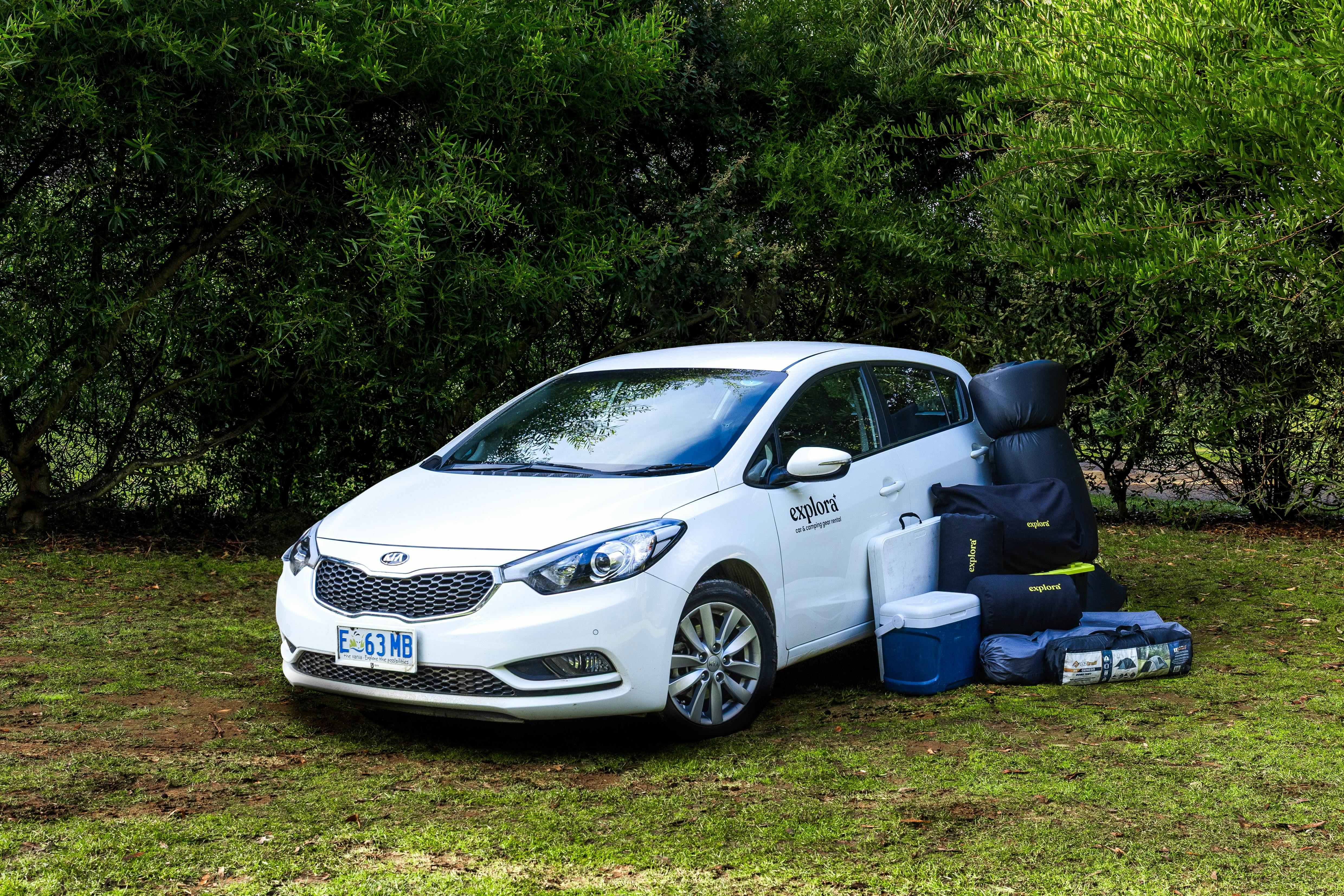 A Kia Cerato with the camping gear standing next to it