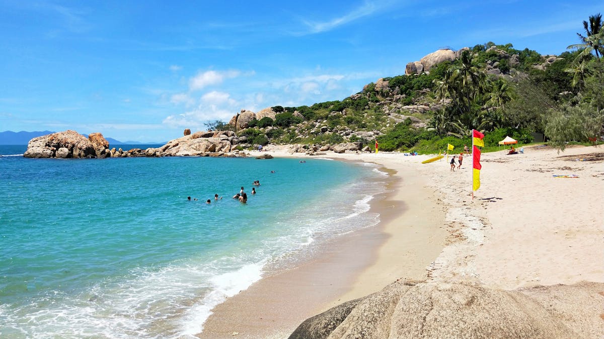 People swimming and life guard on sandy beach in protected bay