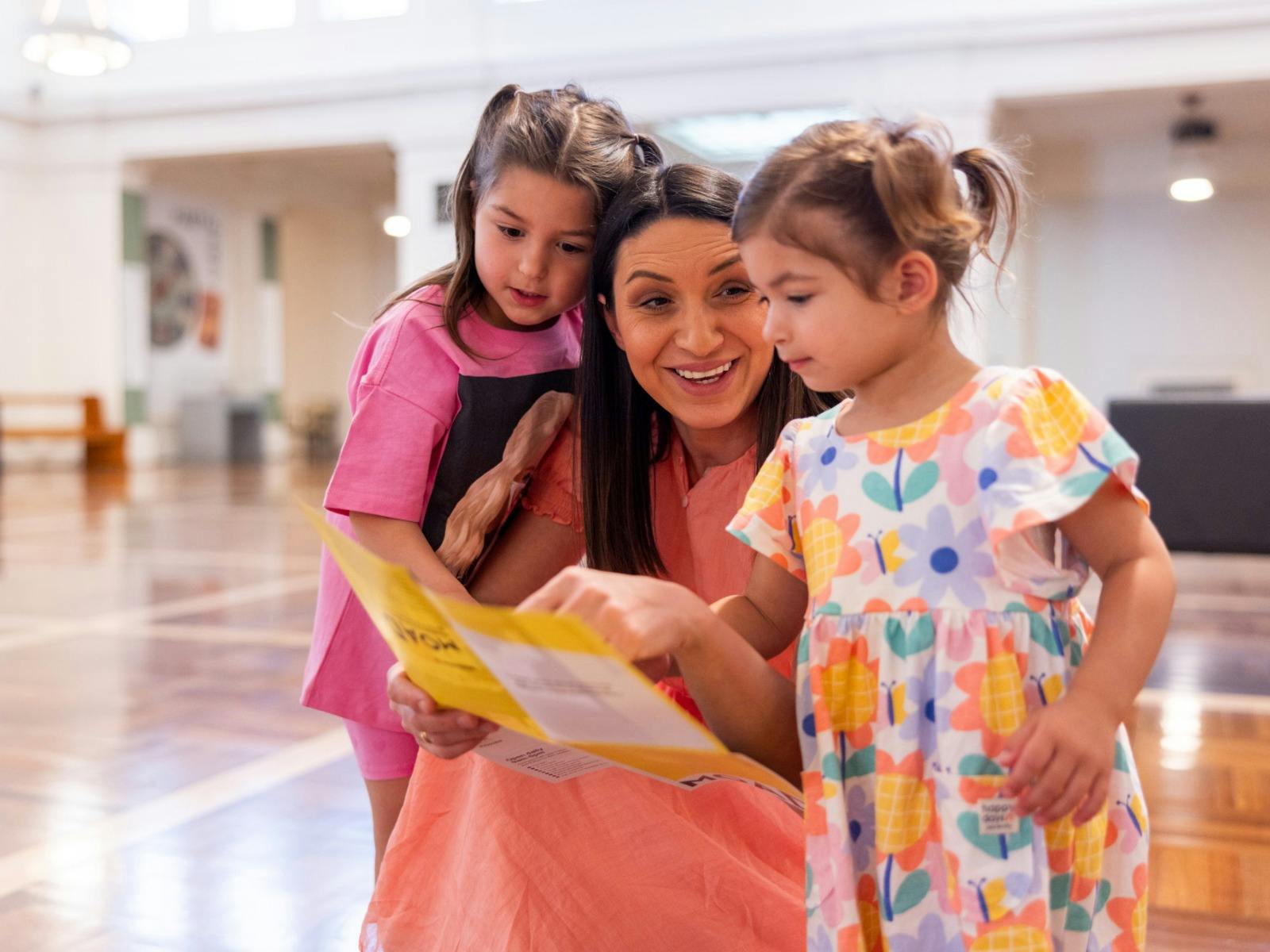 A mother and her young daughters looking at the museum map