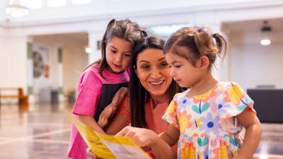 A mother and her young daughters looking at the museum map