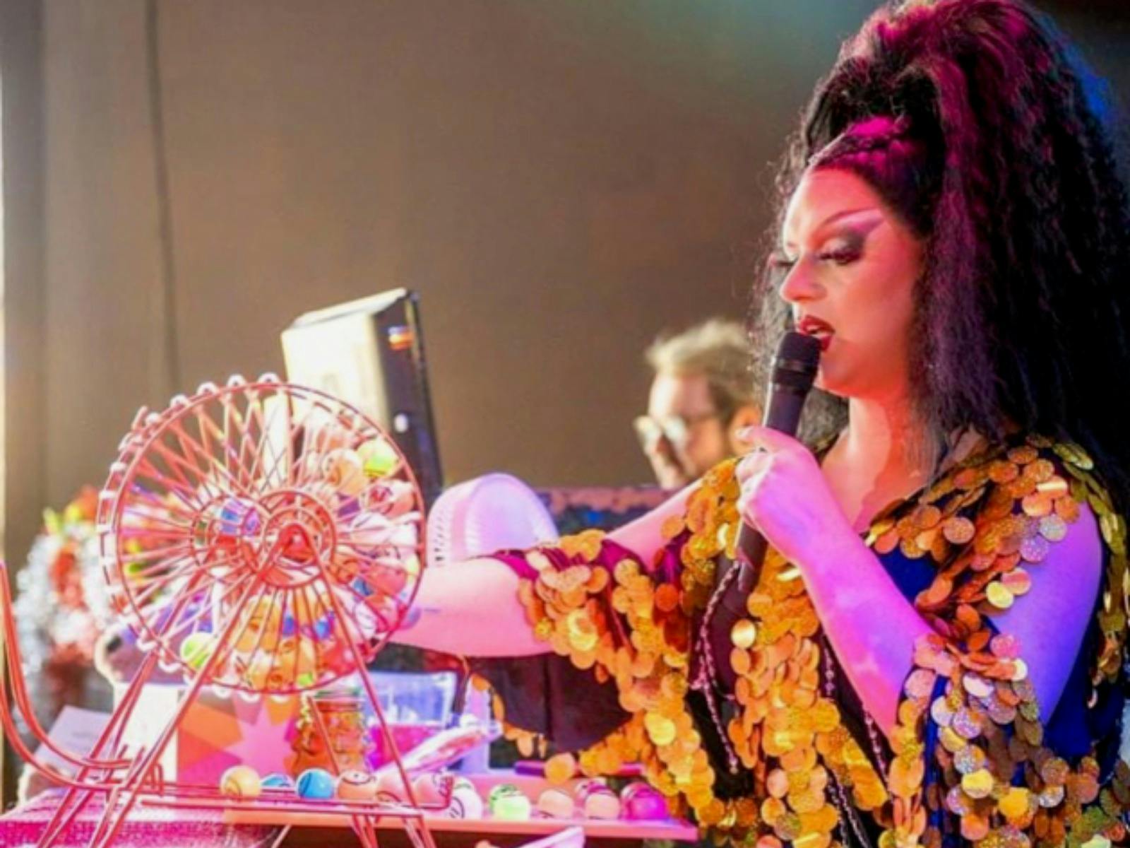 Drag Queen reading Bingo Numbers with a spinning Bingo Toy