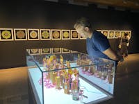 A man looks at a vitrine containing contemporary art sculptures in a darkened gallery with prinrs