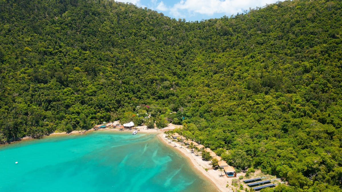 Aerial view of mountains and rainforest surrounding a small beach resort