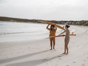 Two woman by the beach with longboards