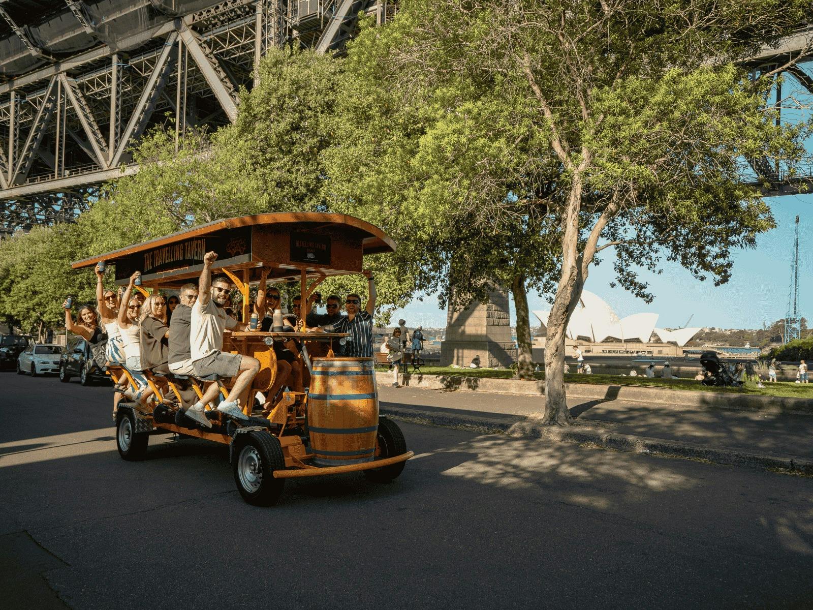 Group of people enjoying a unique cycle on the Travelling Tavern under Sydney Harbour bride