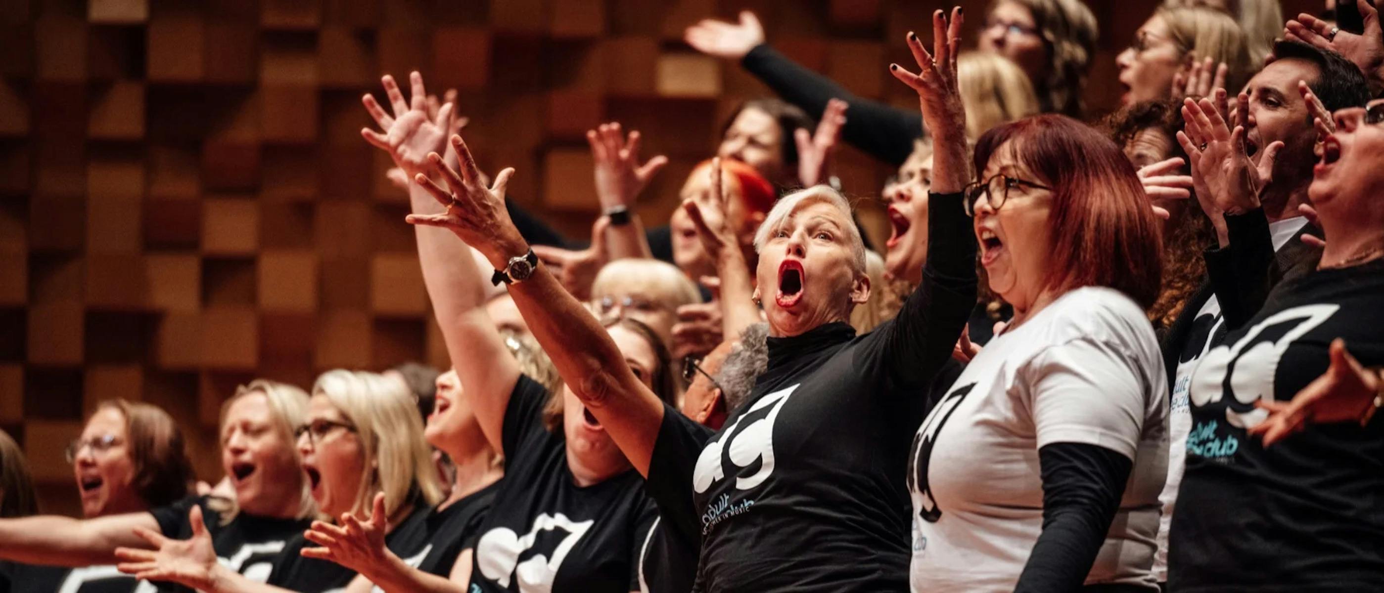 A group of people singing with their hands in the air