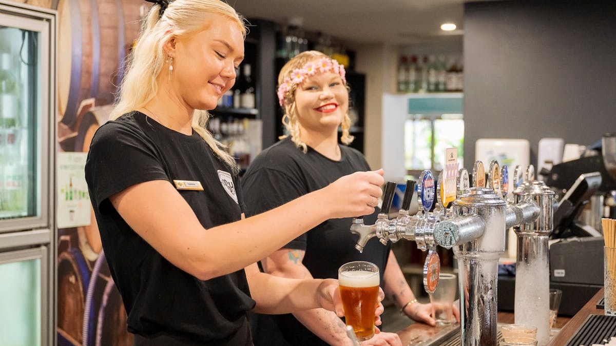 two female staff members smiling at the Reef Gateway Hotel bar area