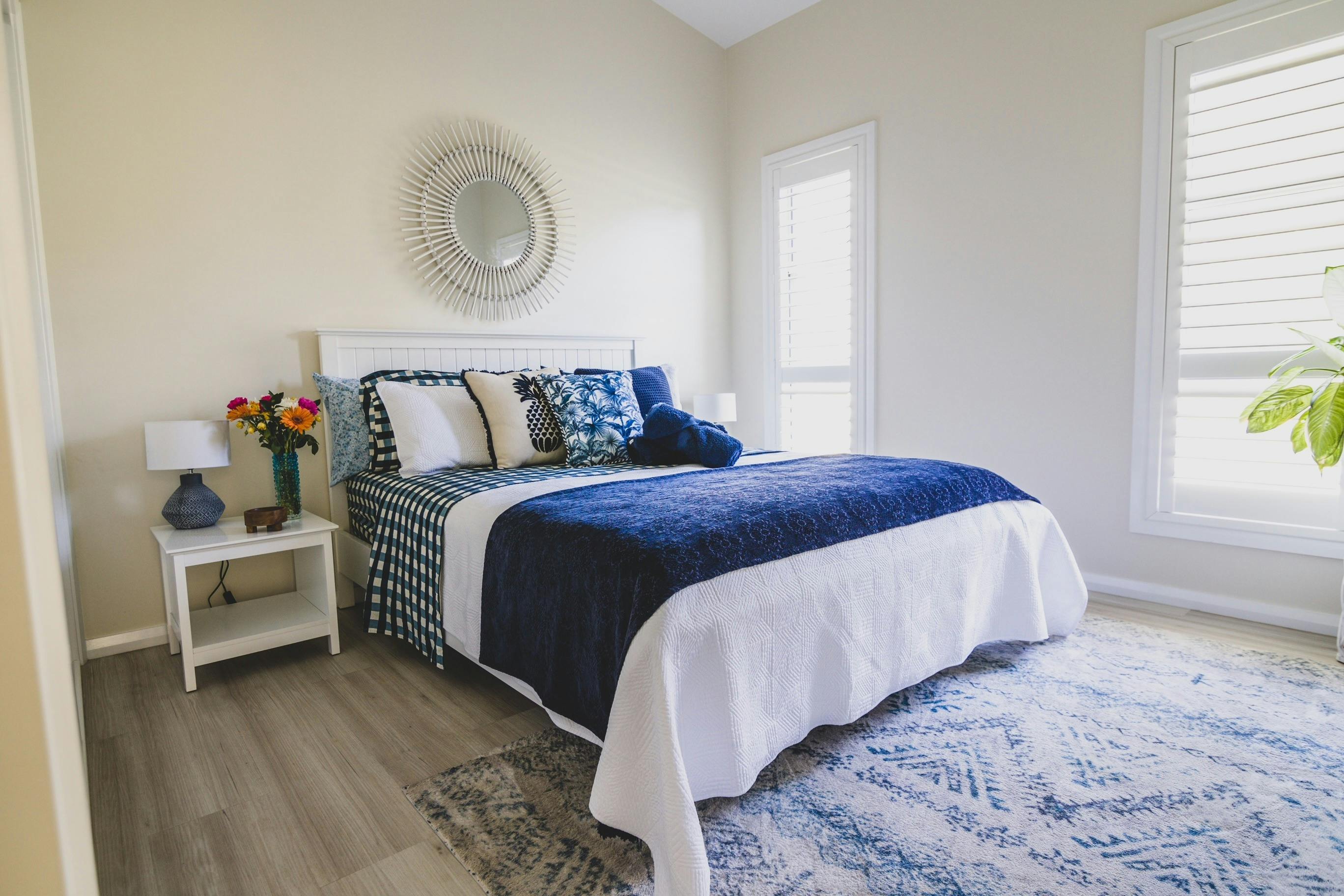 Bedroom with bed covered with qhite coverlet and blue throw rug