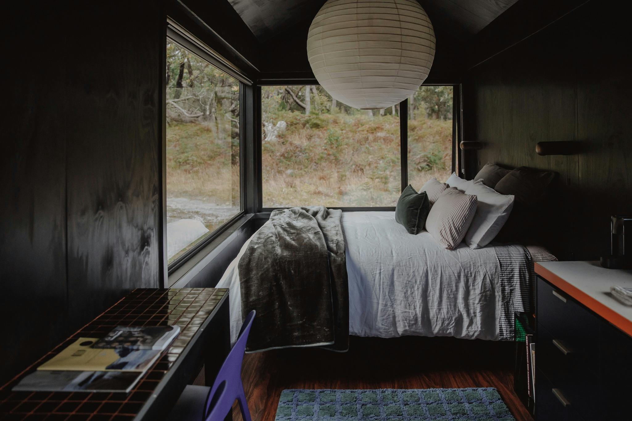 A queen bed under a large pendant light with a breakfast bar in the foreground