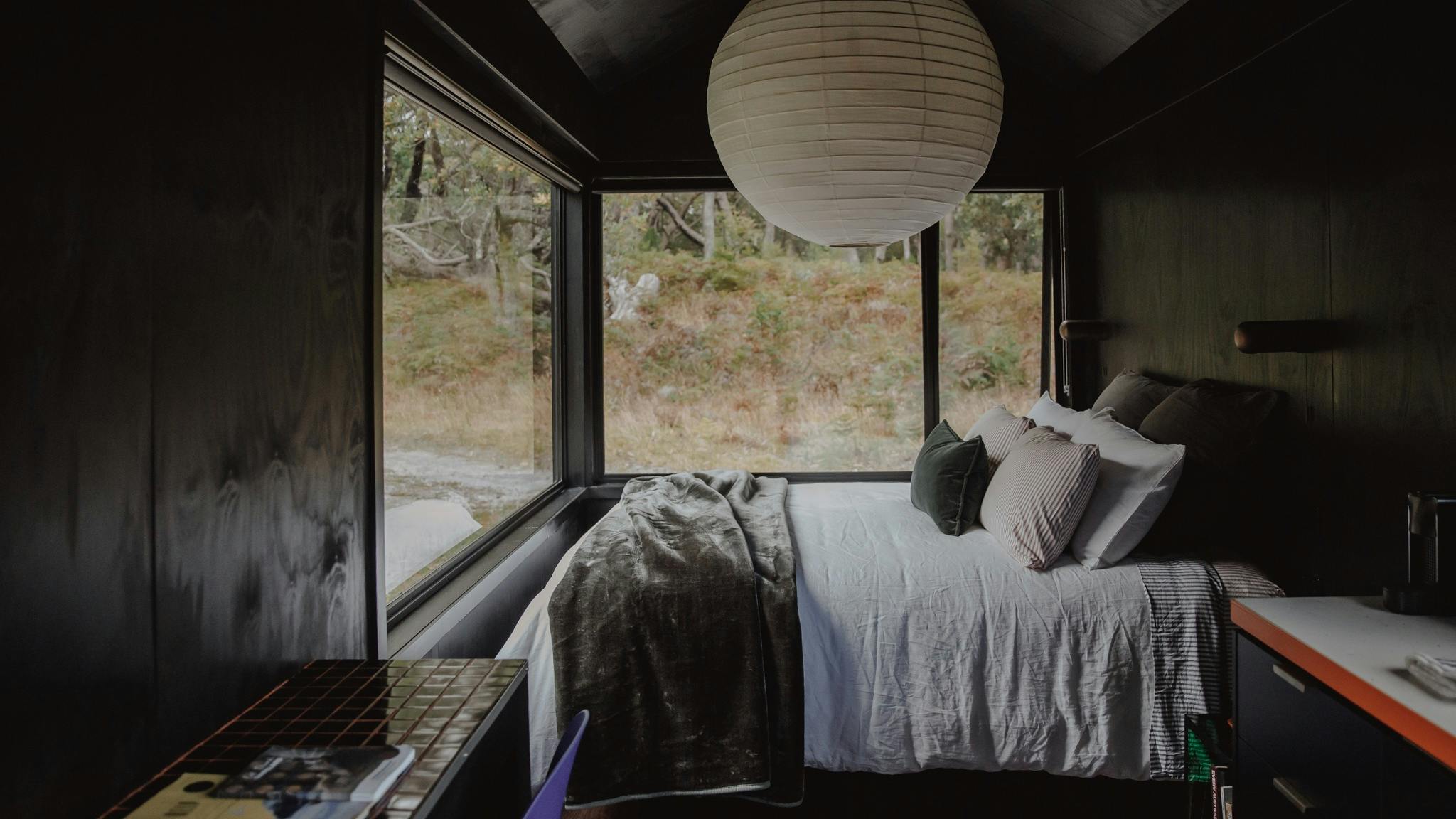 A queen bed under a large pendant light with a breakfast bar in the foreground