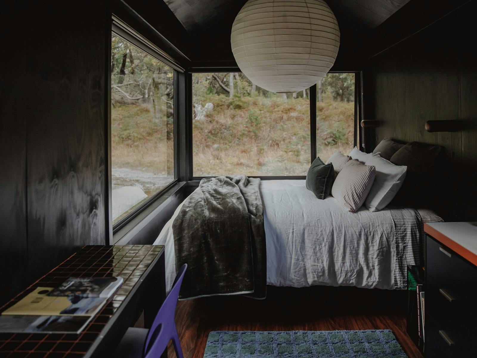 A queen bed under a large pendant light with a breakfast bar in the foreground