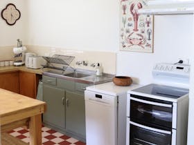 Kitchen with Smeg coffee machine, electric stove top and oven and dishwasher.