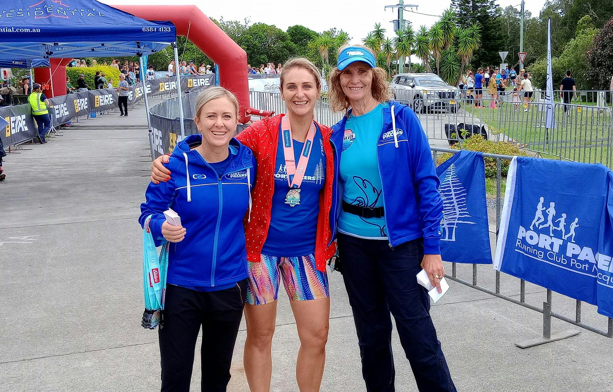 One participant with a medal and two volunteers.