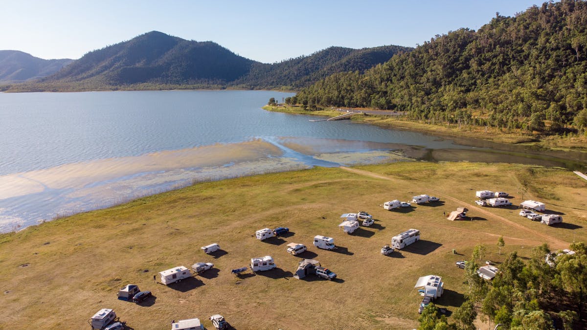 Caravans and campers at the Lake Proserpine with rolling hills in the background