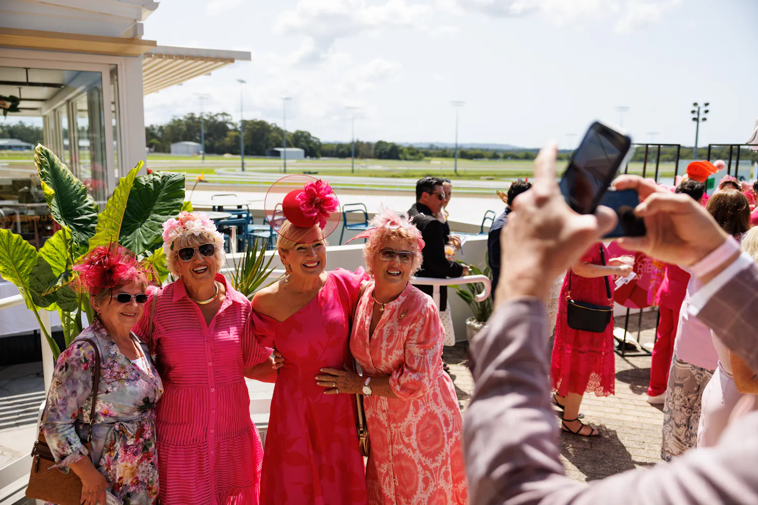 Four ladies smiling at the camera having their photo taken wearing pink dresses