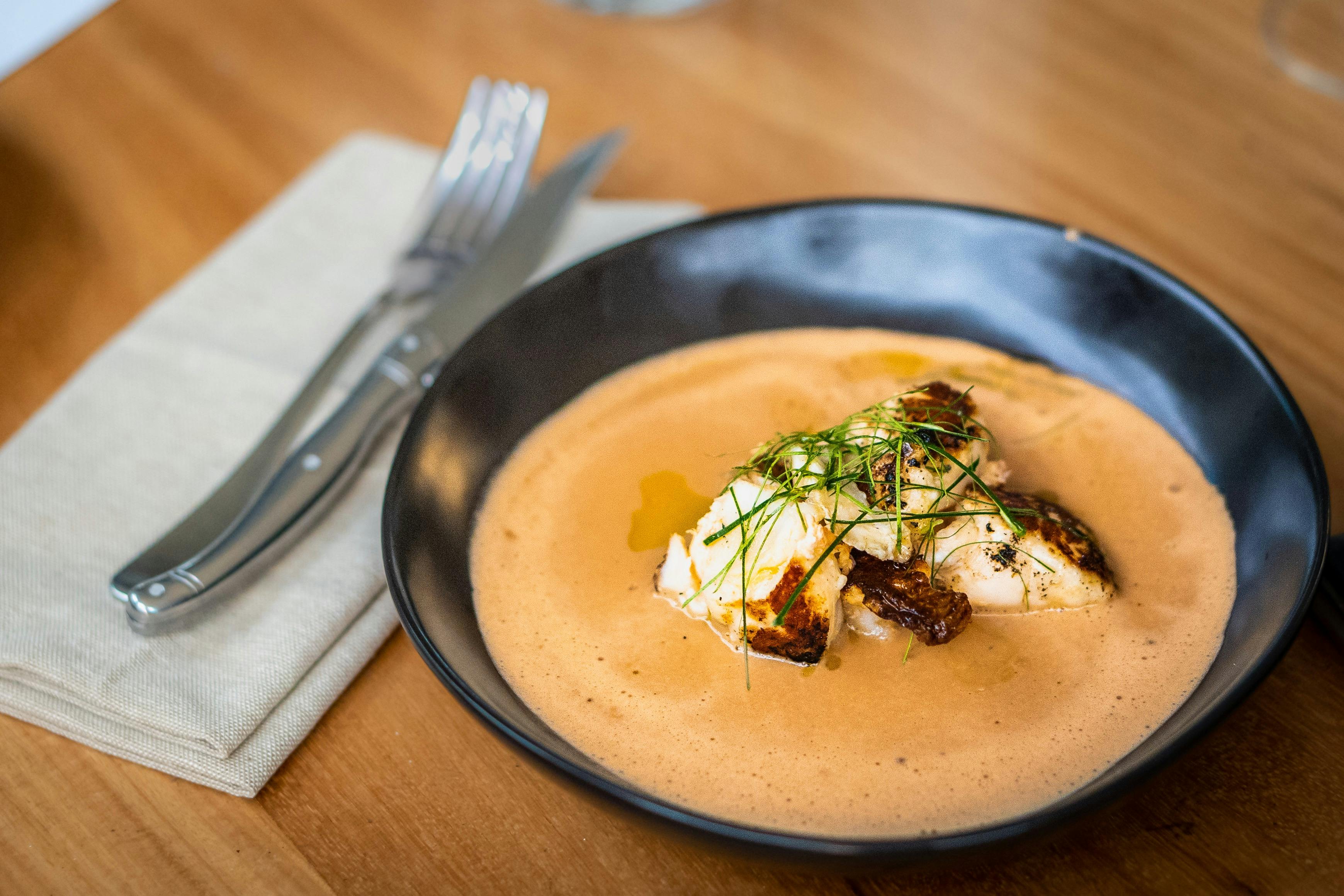 Guyala's Painted Cray & Bisque dish on a table, with cutlery
