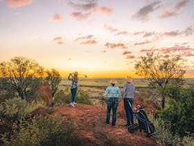Female golfer tees off from Jump Up in Winton Outback Queensland with two golfers watching on.