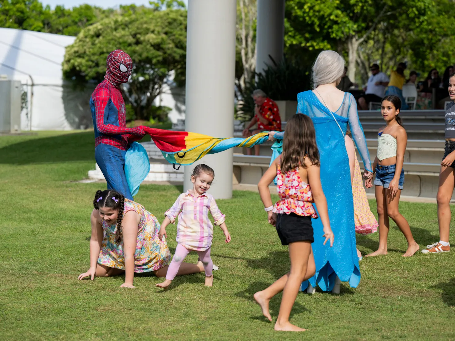 Spiderman and Elsa playing limbo with young kids