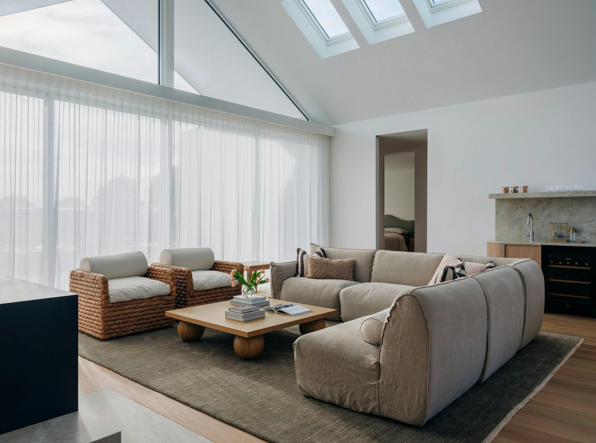 Cosy lounge area with a large L shaped couch, armchairs, coffee table, rug, fireplace