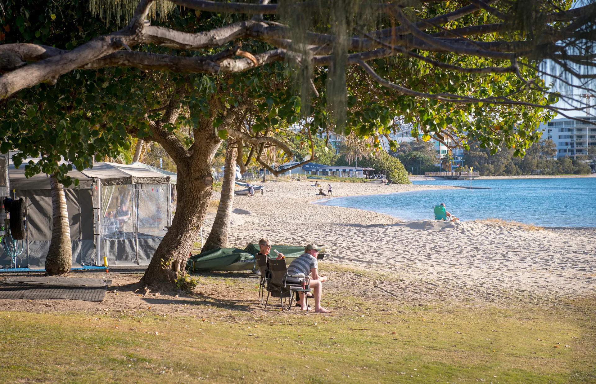 Image of a water front site at Cotton Tree Holiday Park with views of the water and a couple sitting