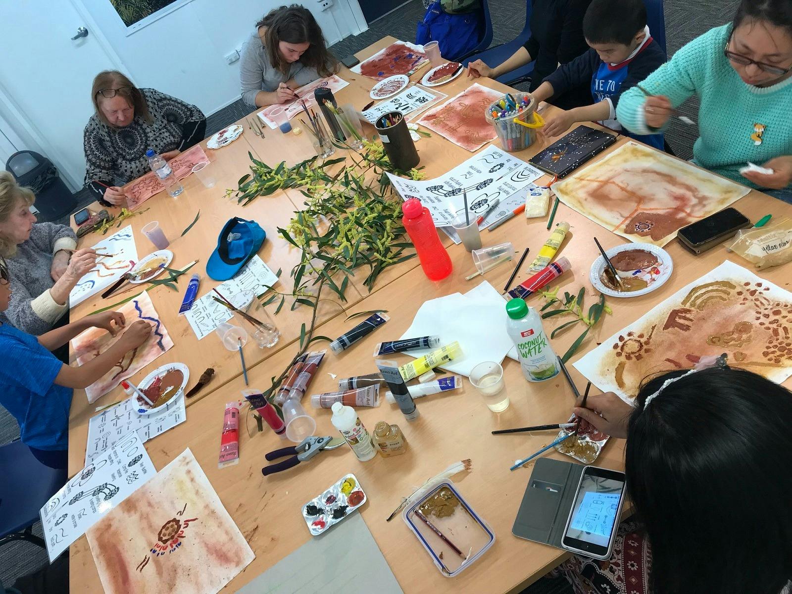 A table with people working on some artwork in a workshop