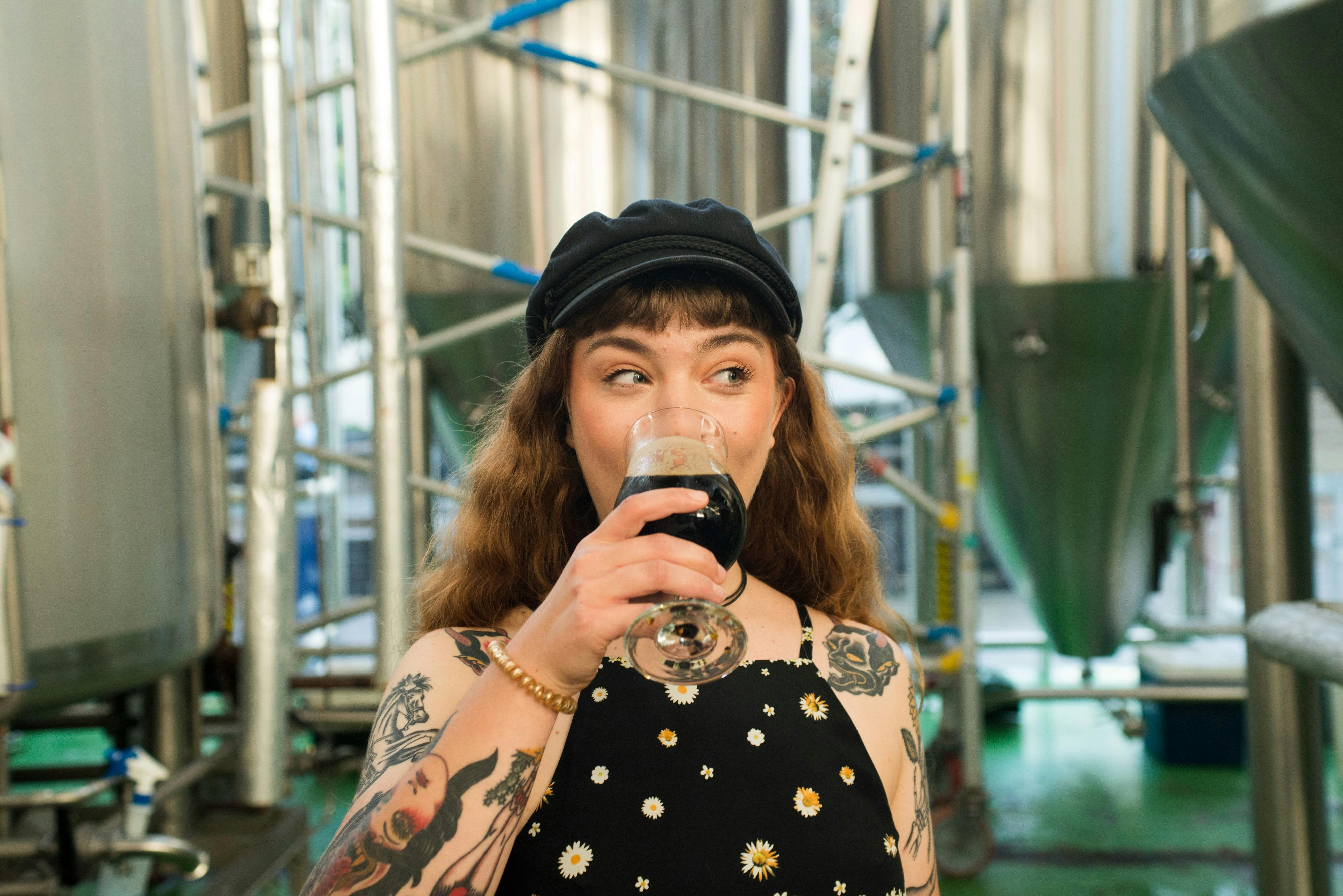 Cool woman drinking beer in brewery