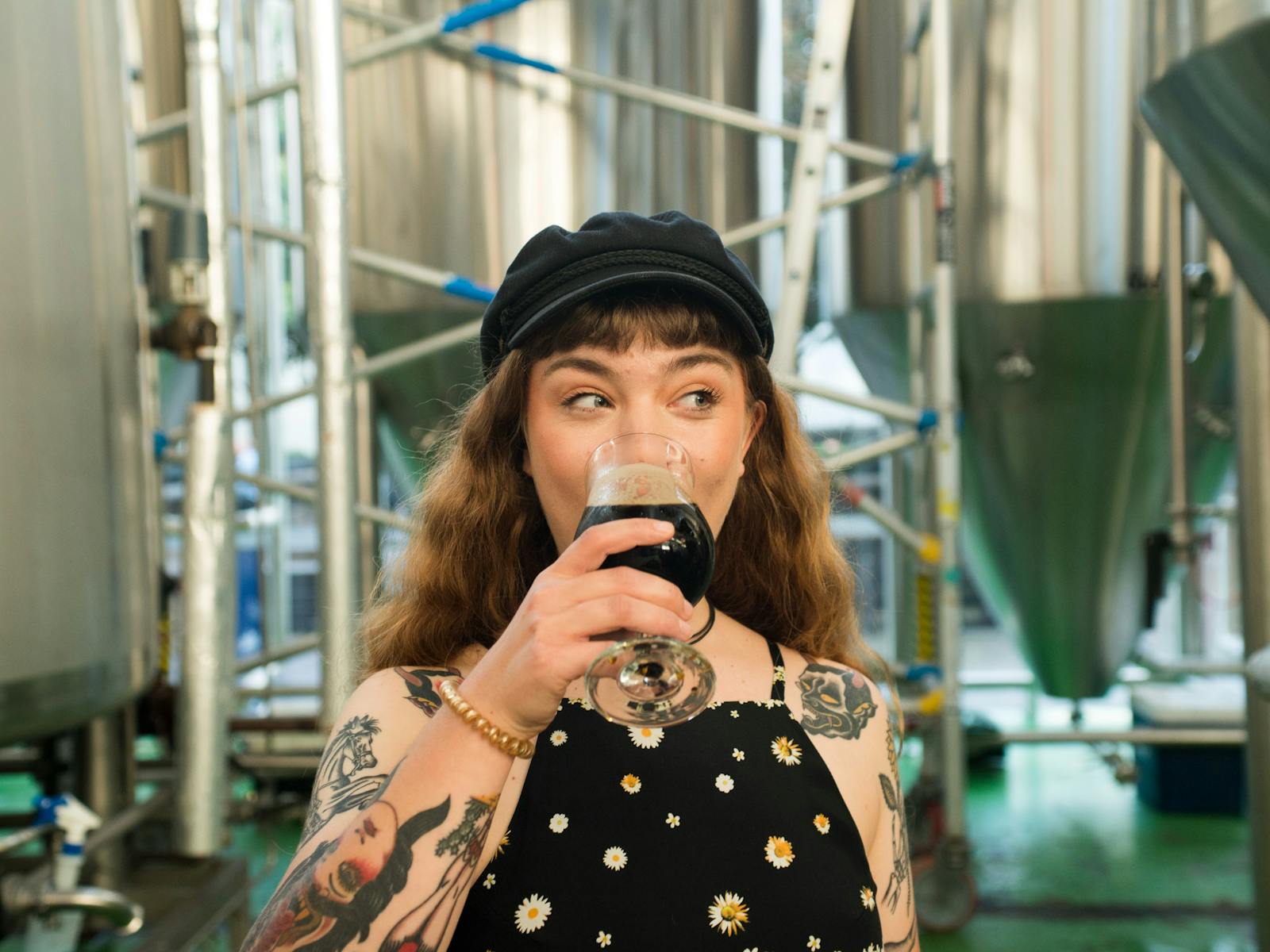 Cool woman drinking beer in brewery