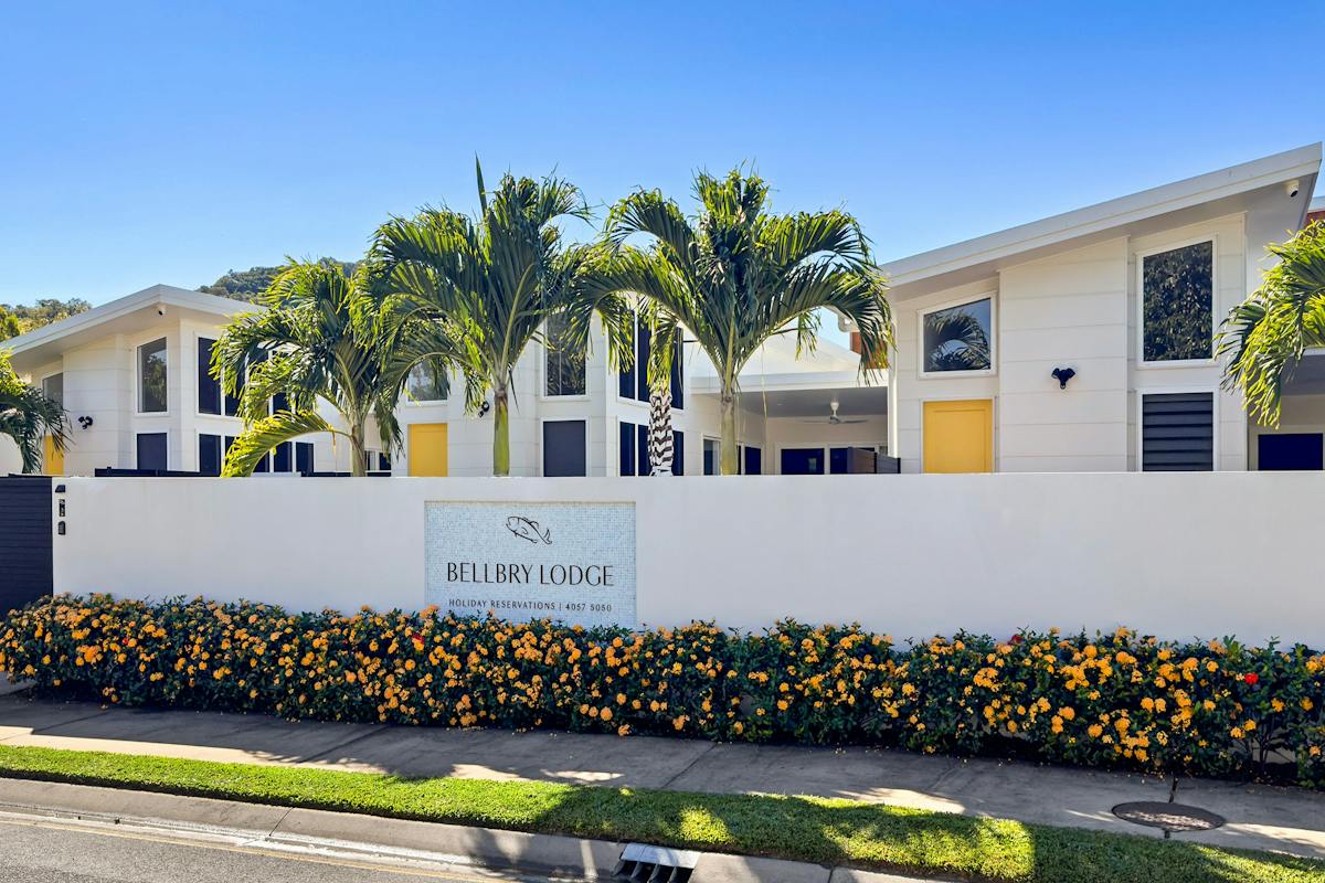 View of Bellbry Lodge from street with signage , buildings, palm tress and golden doors