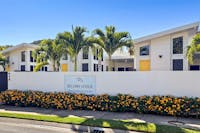 View of Bellbry Lodge from street with signage , buildings, palm tress and golden doors