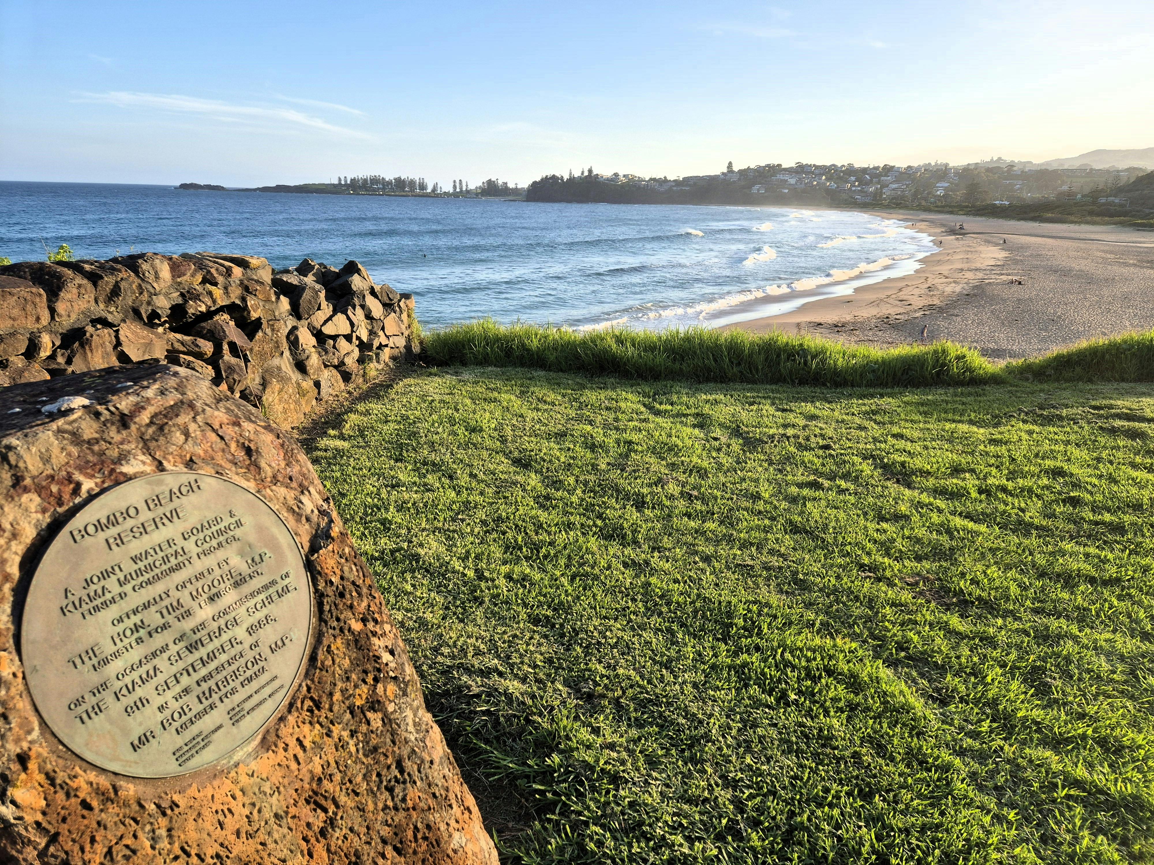 Plakette und Grasland, die zu einem Sandstrand führen