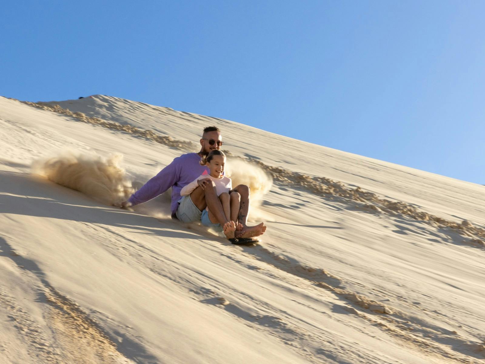 Child and Dad sliding down the sand dune
