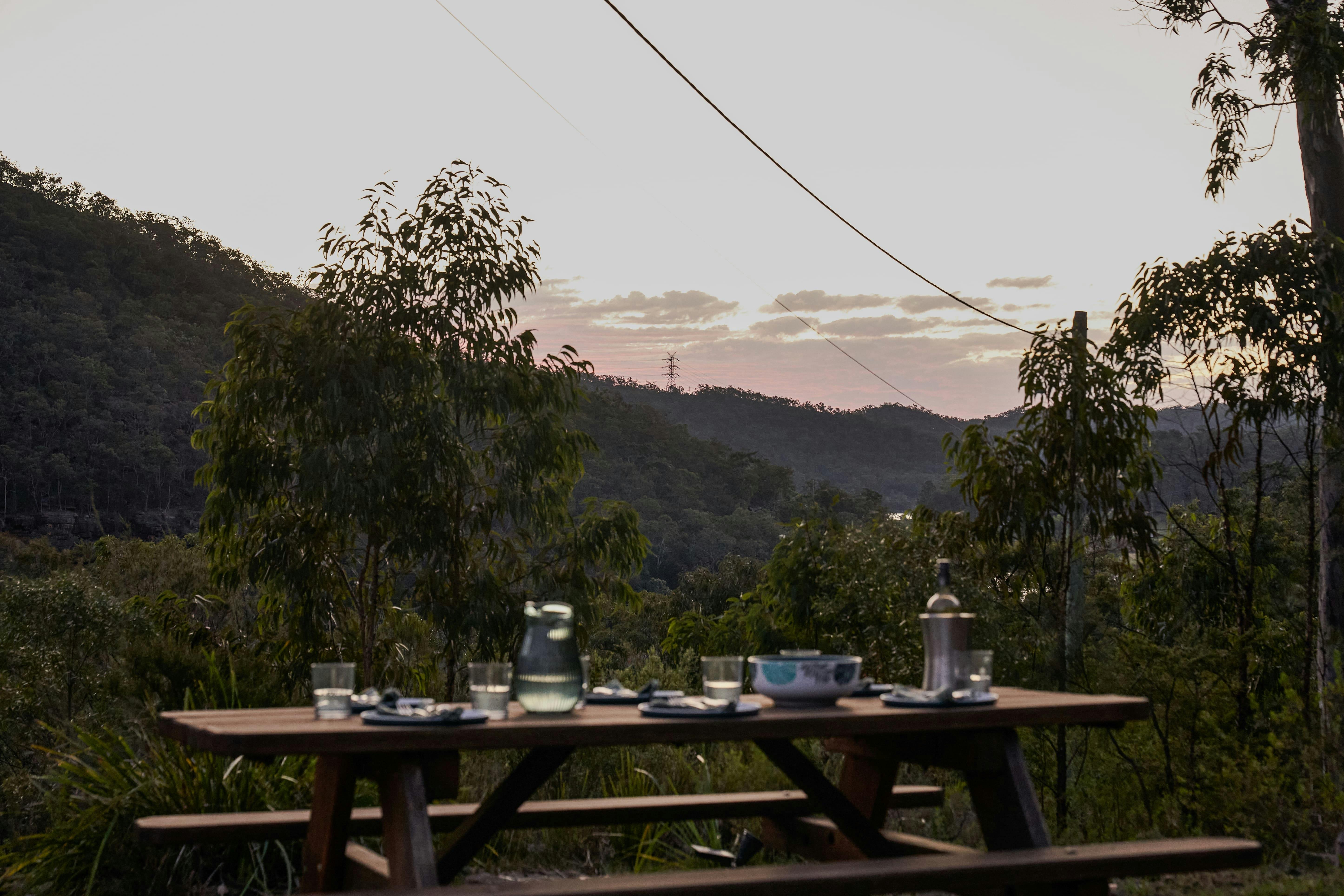 Outdoor picnic table set for meal with valley and river views