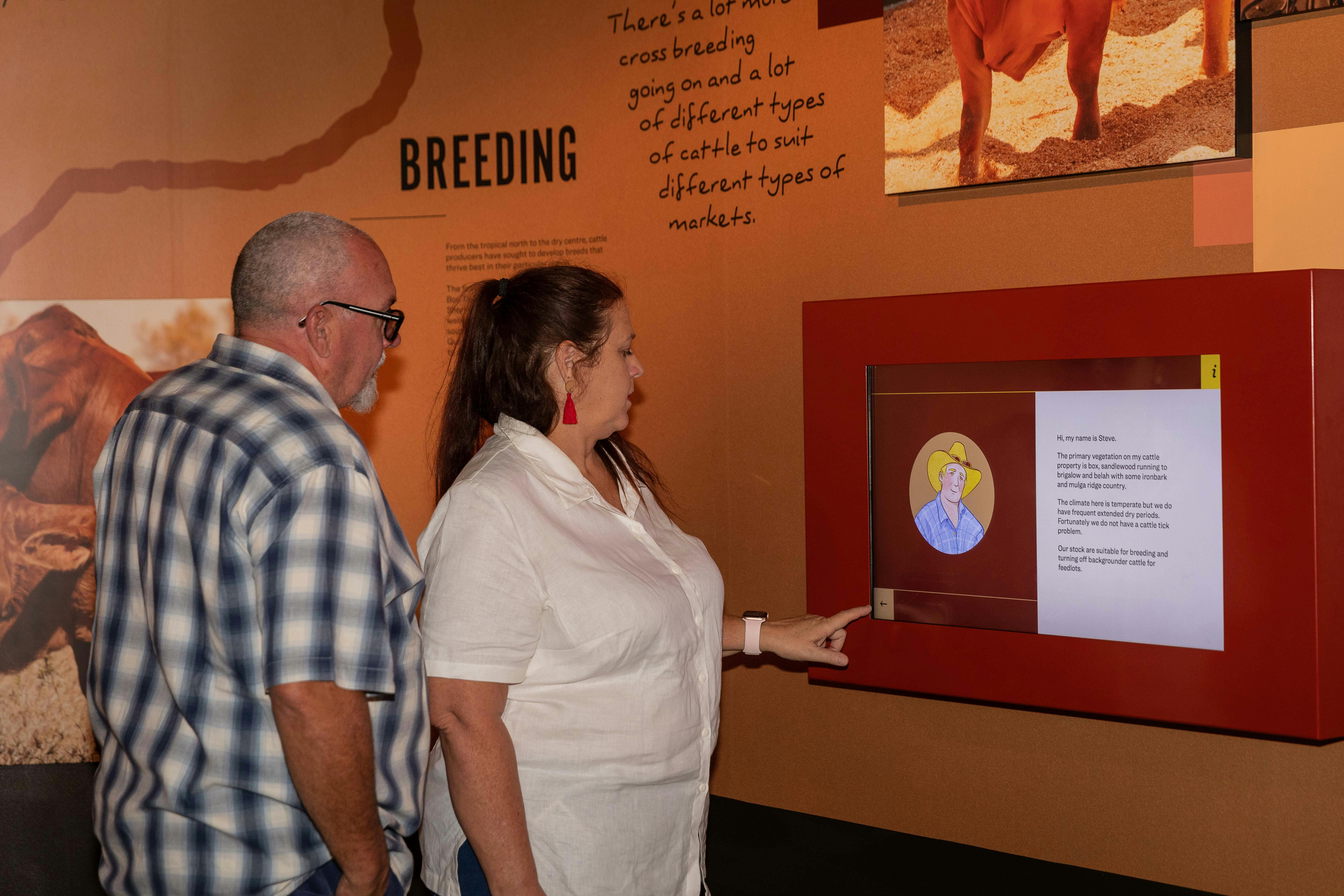 A woman in a white shirt presses a button on an interactive exhibit