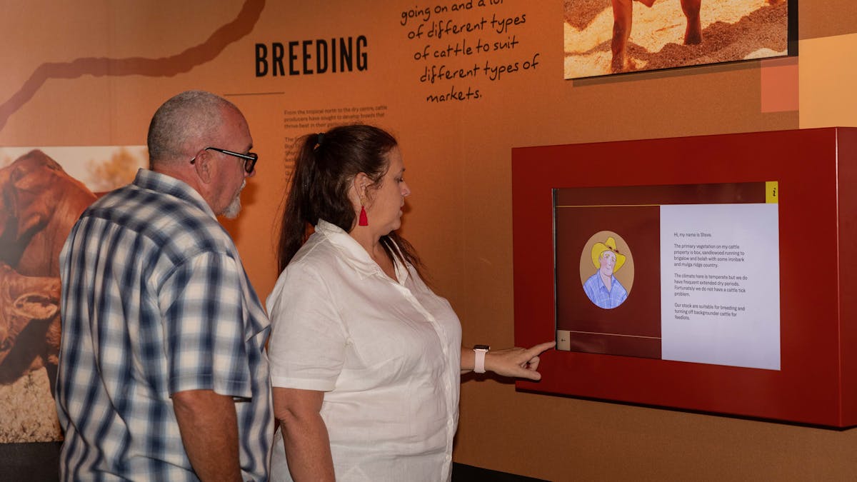 A woman in a white shirt presses a button on an interactive exhibit