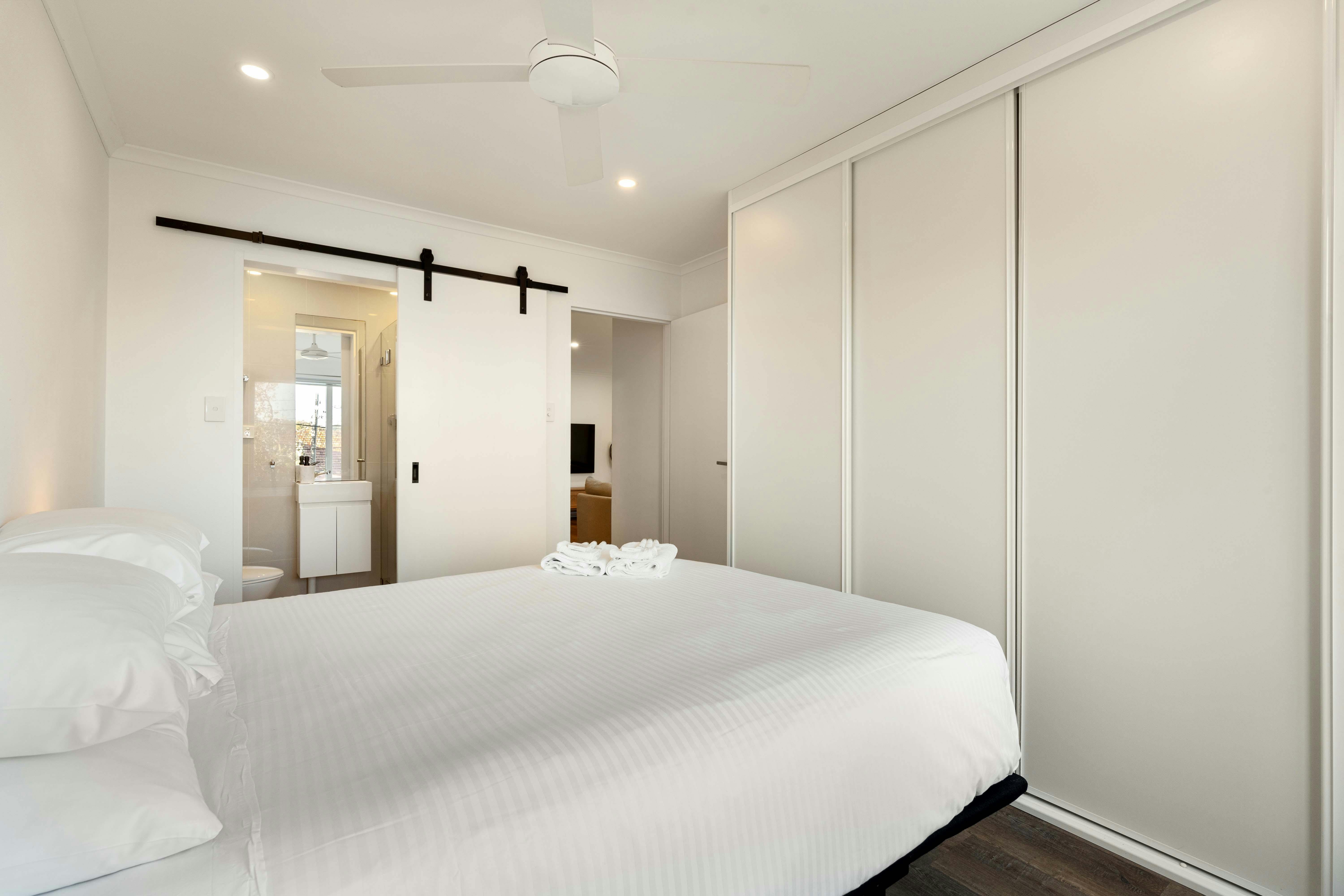 Cozy bedroom with a fan, clean linens, and ensuite bathroom.