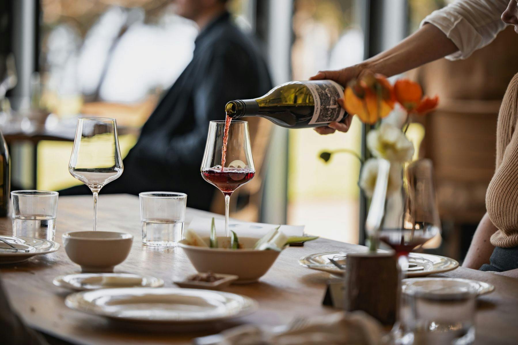 Waiter pouring a glass of red wine