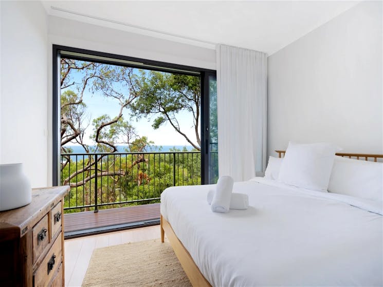 King bed with a large window showcasing beautiful lush views