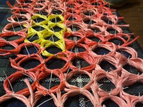 Coloured baling twine twisted into a honey comb pattern of pink, red and yellow.