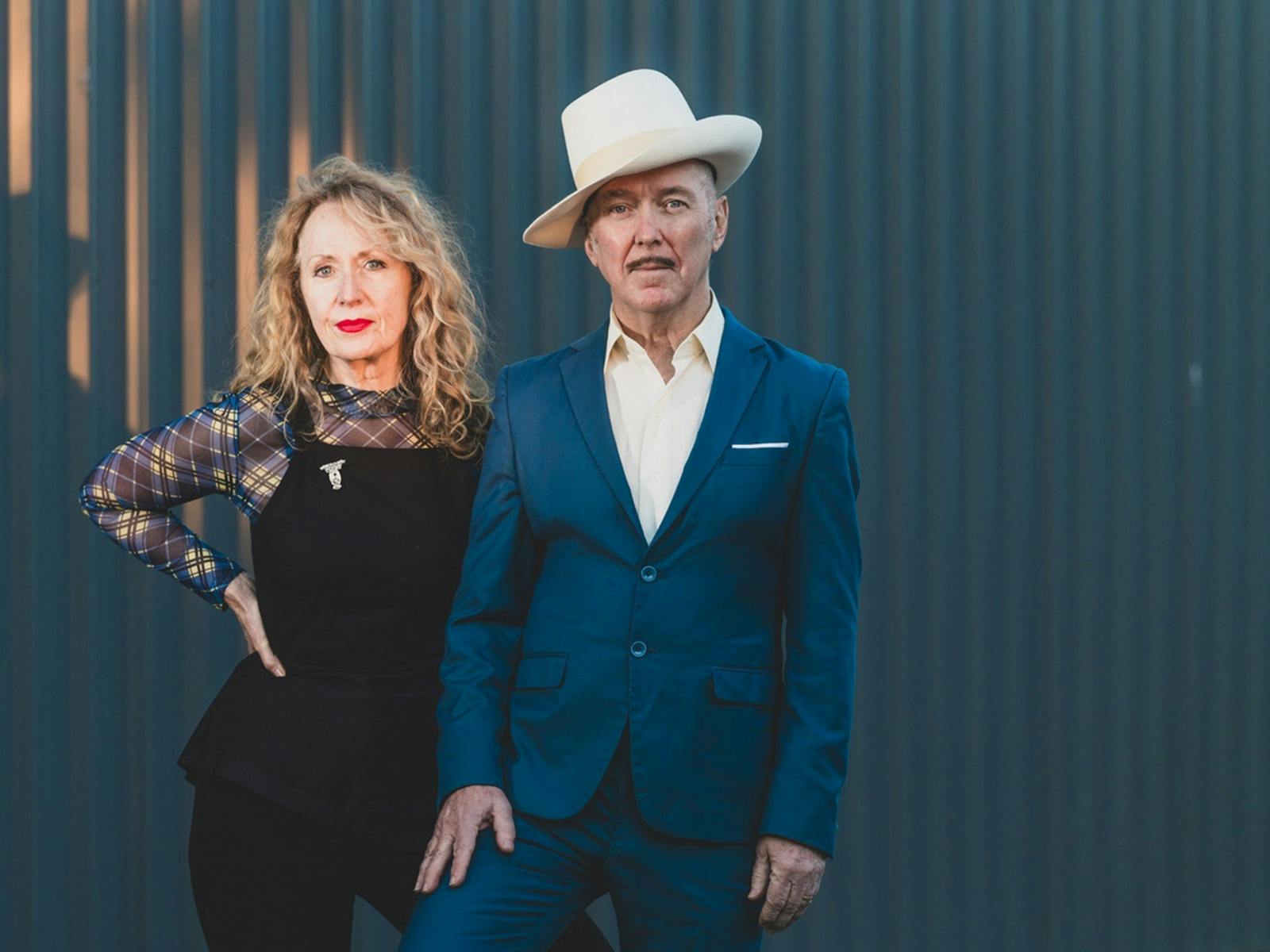 Dave Graney & Clare Moore stand in front of a blue wall Dave Graney & Clare Moore stand in front of a blue wall