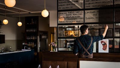 A man writes a menu on a large window glass.