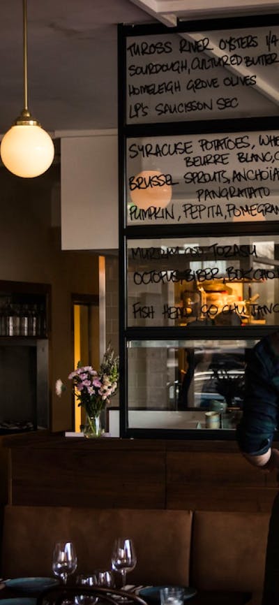 A man writes a menu on a large window glass.