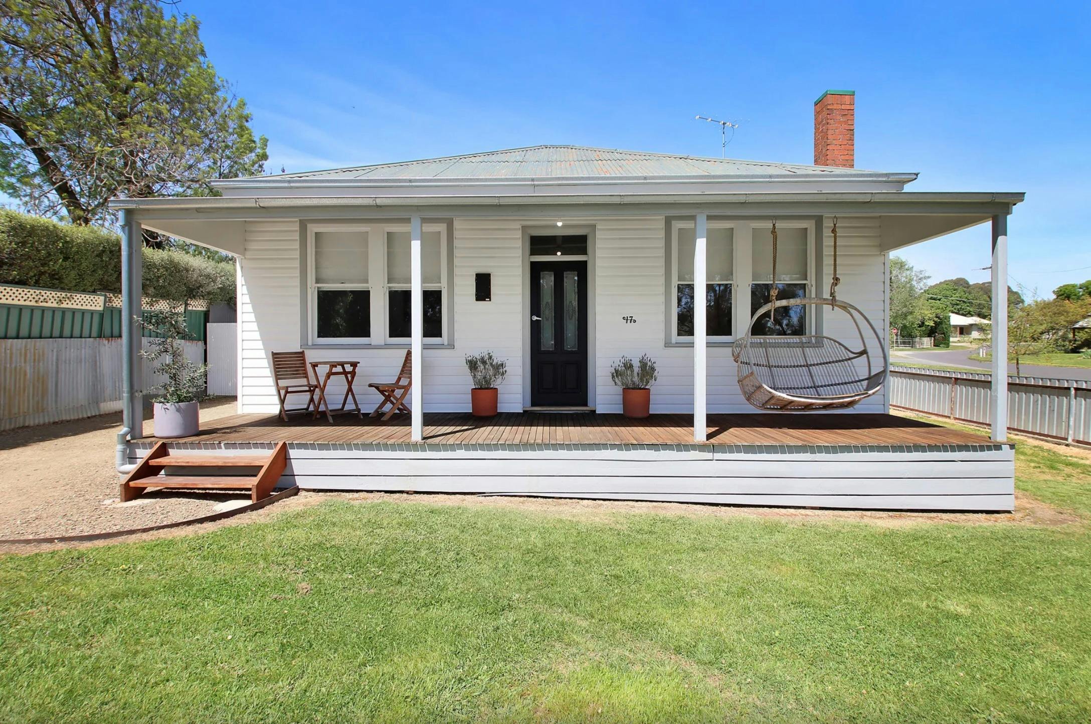 Front of cottage with grassed area and hammock on verandah