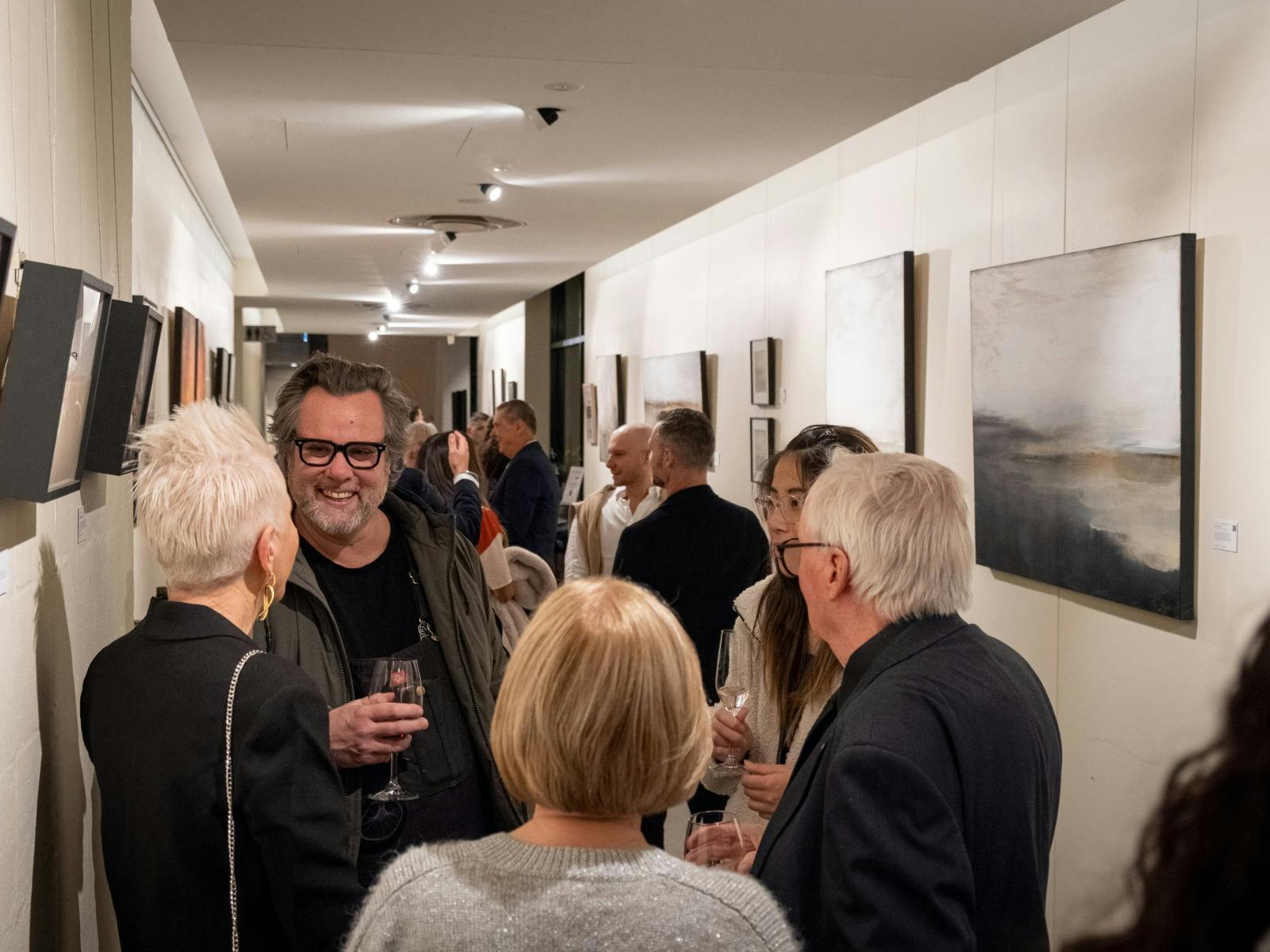 Art gallery opening: guests mingle and chat with wine