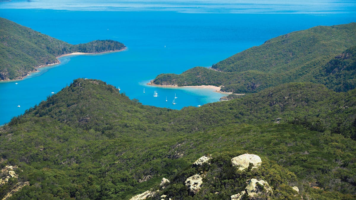 View from the hilltop overlooking the sailing boats in blue ocean and other islands in distance